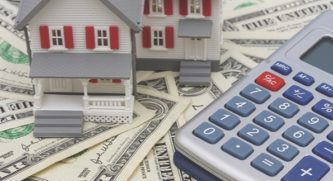 Two play houses and a calculator sitting on top of a stack of money