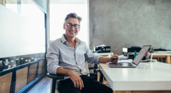 Mature Male Business Owner Man On Computer At Desk In Office