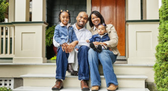 Family sitting on the steps of a house smiling