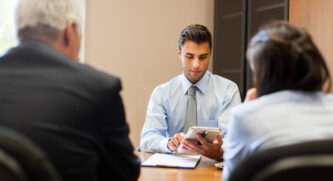 Banker filling out a form on a tablet for a couple he's helping
