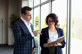 Man pointing to a women's notebook while she writes something down