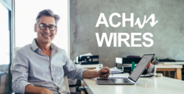 Man sitting at a computer with a pen in his hand smiling at the camera. Image also says ACH Wires